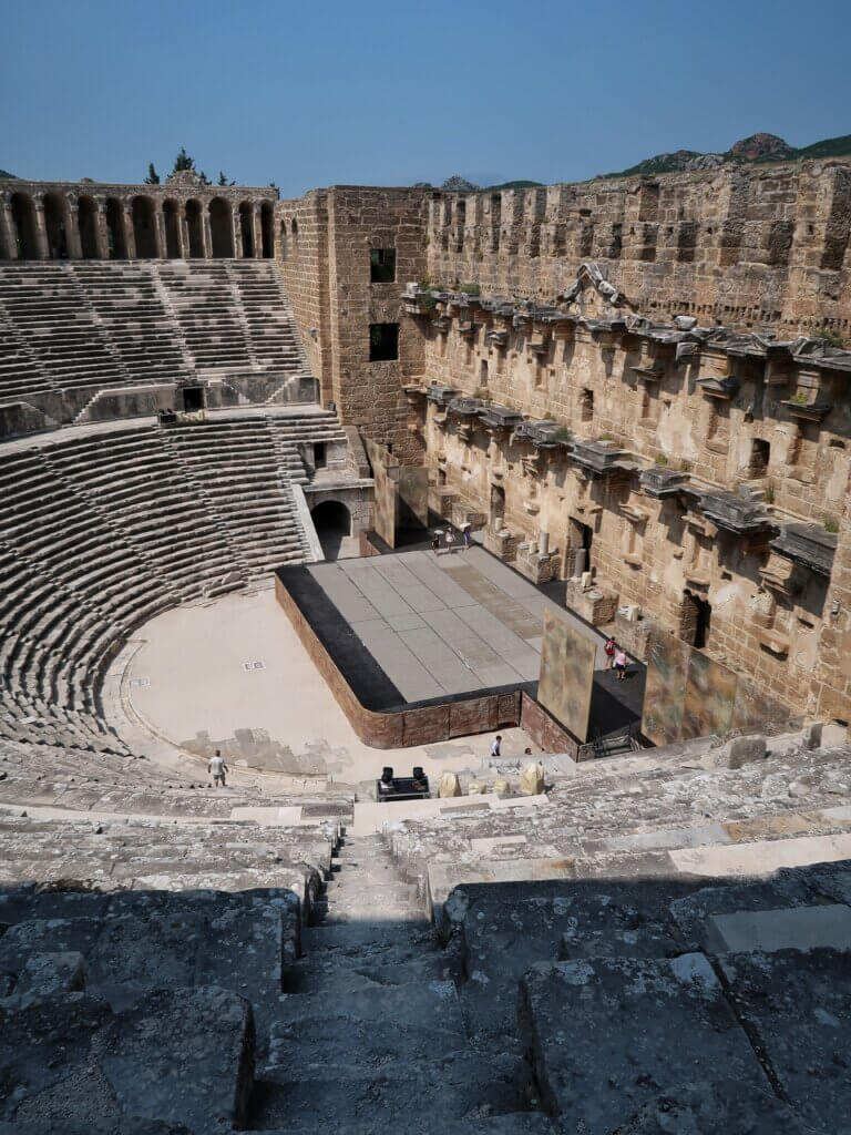 Blick von den oberen Sitzreihen auf Bühne und Bühnengebäude des Theaters von Aspendos